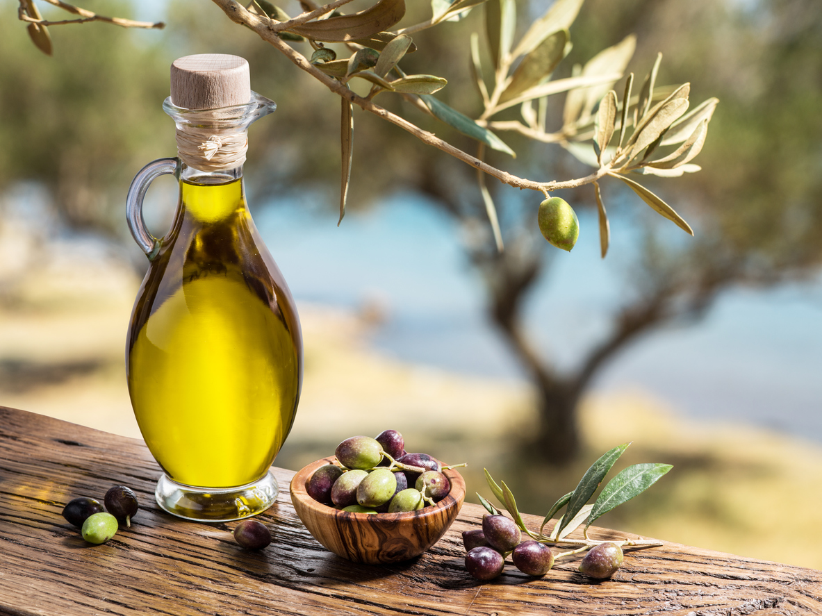 Olive oil and berries are on the wooden table.